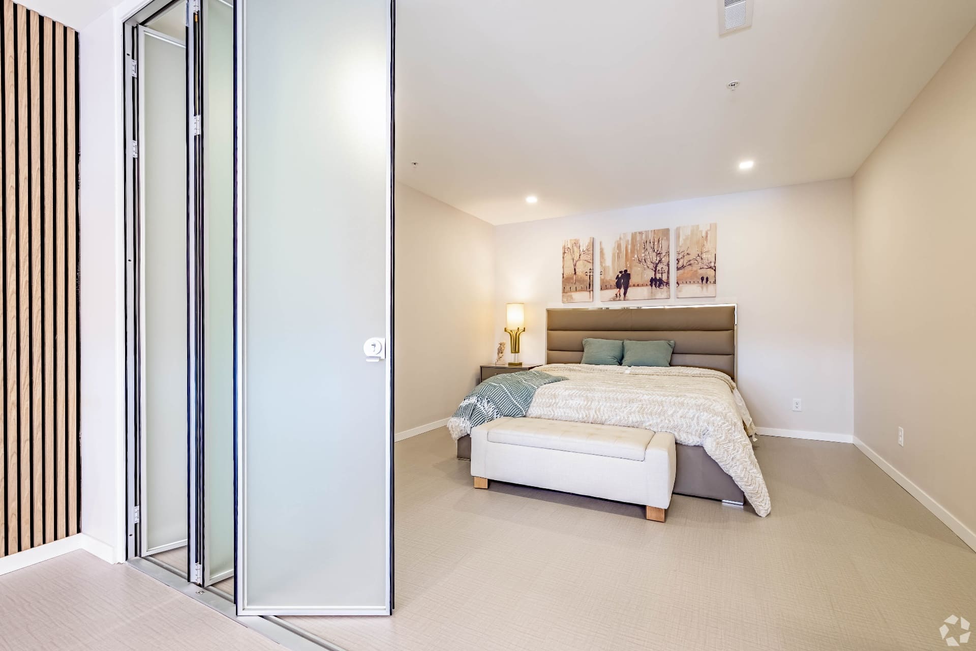 Model bedroom with upholstered headboard and frosted glass closet